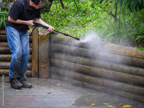 Obraz na płótnie Man cleaning retaining wall using a pressure washer. w salonie