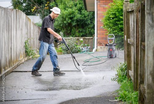 Obraz na płótnie Man washing concrete driveway using a pressure washer. w salonie