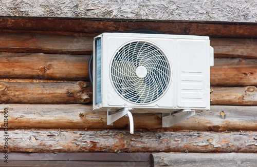 A white air conditioner is mounted on a wooden wall