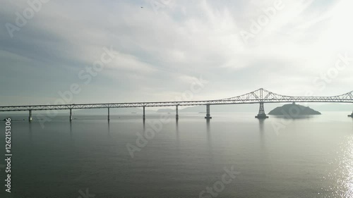 Left to right drone perspective of the Richmond–San Rafael Bridge spanning the bay at Point Molate.