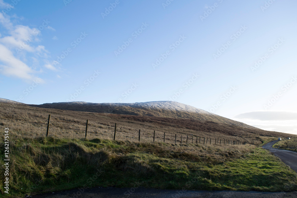 Naklejka premium A view of the Mourne mountains with a fence and a road as leading lines