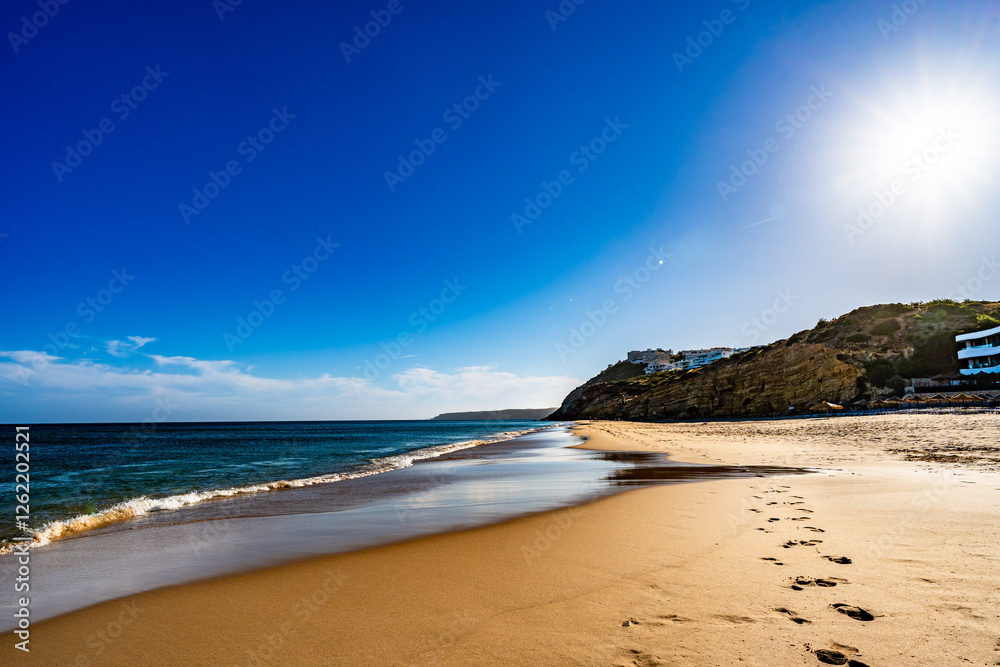 Obraz premium Empty Amado beach in Portugal. Beautiful Algarve coast. View at sunny and sandy beach and cliff