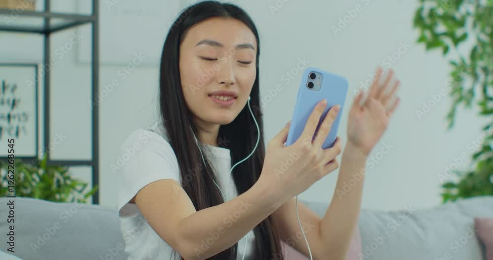 Young Asian woman making video call chat online on mobile phone at home. Talking over video call conference recording vlog. Remote communication at a distance. Young Asian woman making video call chat online on mobile phone at home. Talking over video call conference recording vlog. Remote communication at a distance.