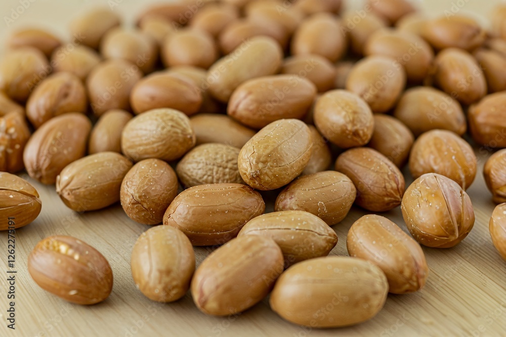 Obraz premium A close-up view of a scattered pile of brown-skinned peanuts on a wooden surface.