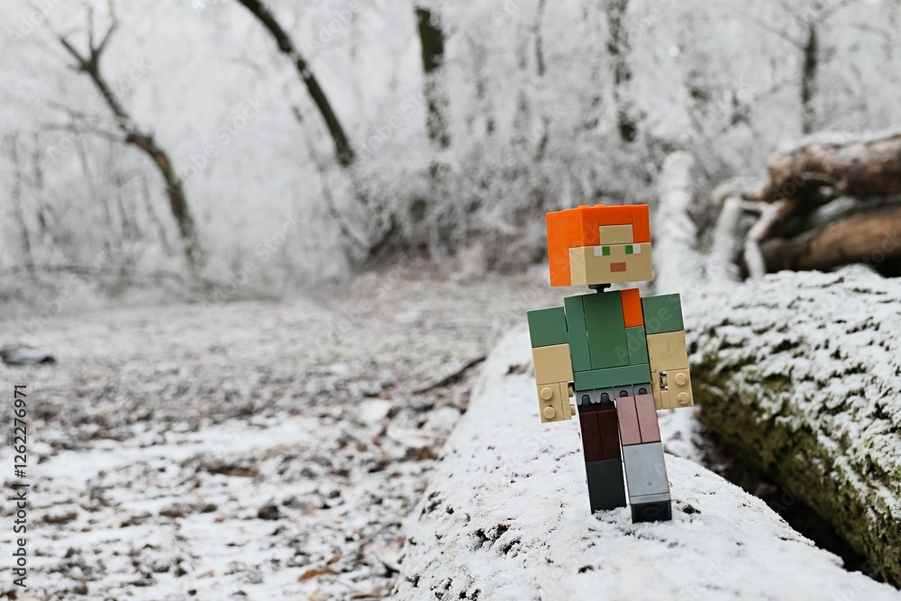 Fototapeta premium LEGO Minecraft action figure of female character Alex walking on chopped down tree logs in heavily frozen winter forest. 