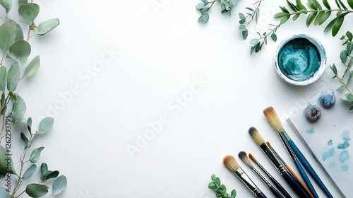 Creative workspace with art supplies and greenery on a clean surface