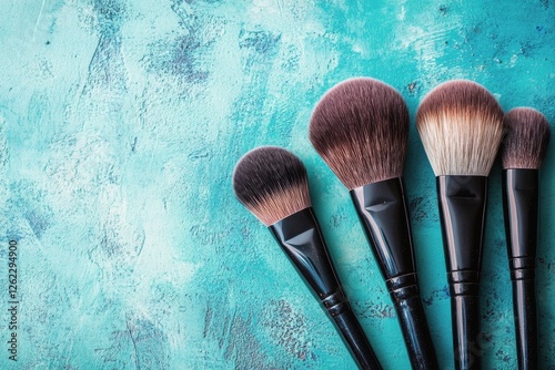 Essential makeup brushes arranged on a textured turquoise background for beau...