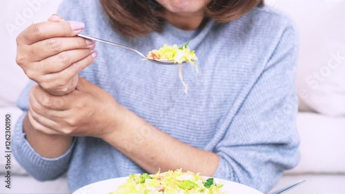 Woman’s hand shaking while holding a spoon, experiencing difficulty eating due to Essential Tremor or Parkinson’s Disease