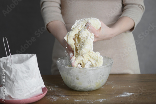 woman makes dough for pasta with her hands in a transparent plate on the table