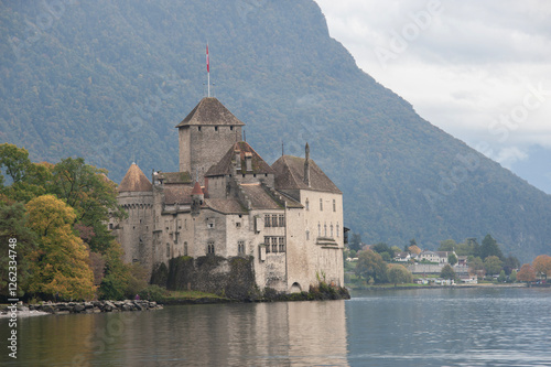 château au bord d'un lac avec des montagnes à l'arrière