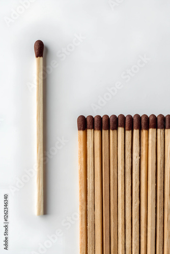 A single matchstick stands upright, facing a row of eleven matches.
 photo