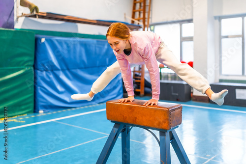 Young gymnast practicing on vaulting horse in school gym