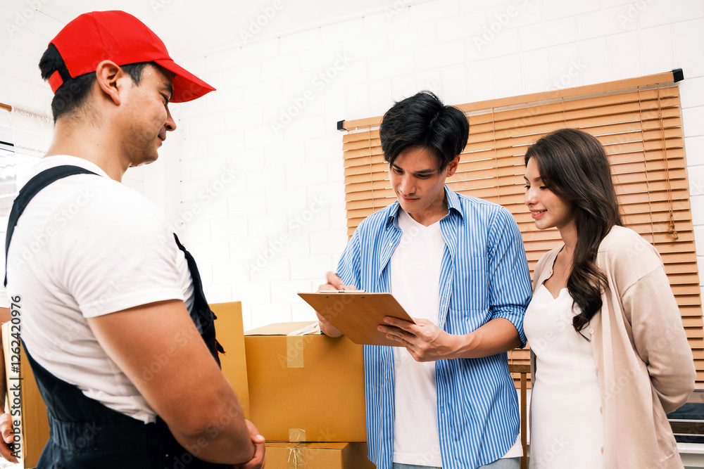 A delivery worker hands over packages to a couple in their new home. Ideal for themes of home moving, relocation, logistics, shipping, Ecommerce, courier service, and online shopping. A delivery worker hands over packages to a couple in their new home. Ideal for themes of home moving, relocation, logistics, shipping, Ecommerce, courier service, and online shopping.