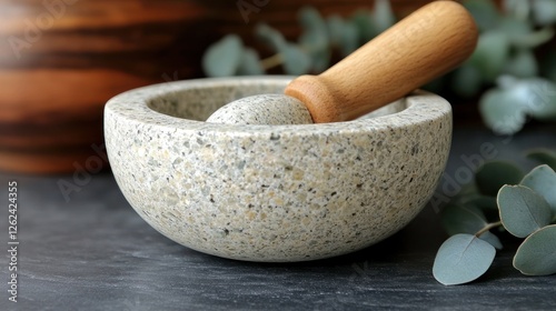 Stone mortar and pestle on dark surface with eucalyptus photo