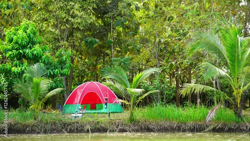 Red camping tent in the riverside forest