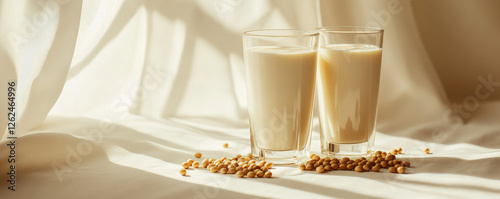 Close up of soy milk in two tall glasses with soybeans scattered nearby, creating warm and inviting atmosphere. Perfect for health conscious individuals