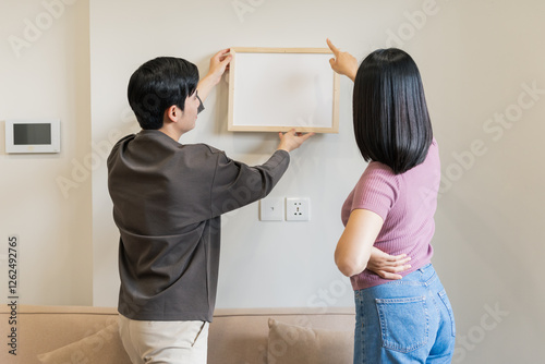 Canvas-taulu The couple hung pictures on the wall together to decorate their new apartment