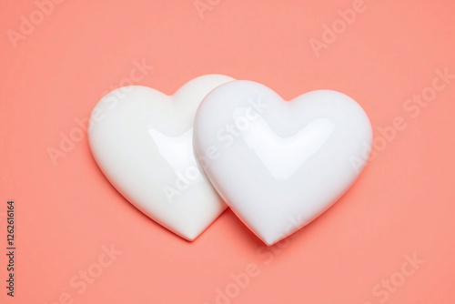 two white heart shaped objects overlapping on coral background