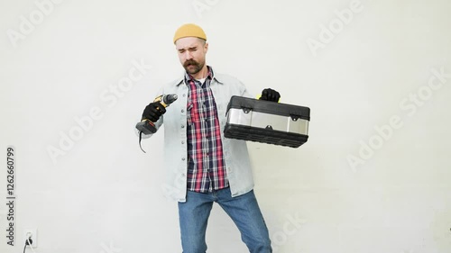 guy is a construction repairman funny dancing on the background of a white wall