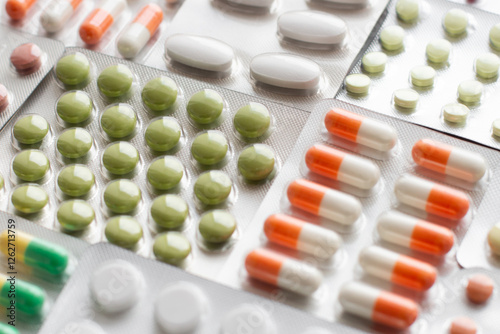 Big pharma metal tablet blister. Multicolor pills medicine. Silver shiny blister with drugs. Transparent capsules in blister pack closeup.