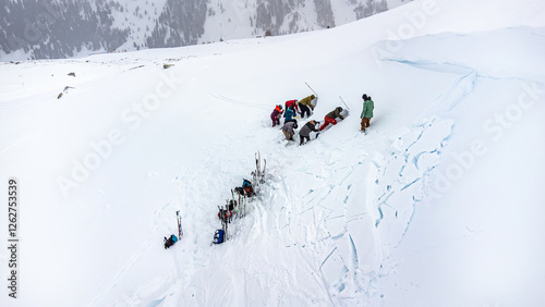 Skitourengänger auf einem Lawinenkegel suchen nach Verschütteten während einer Übung mit Bergführer