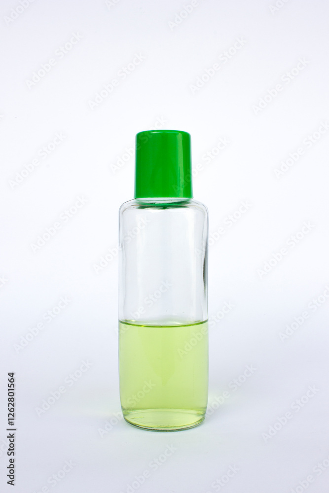 A transparent bottle with a green cap. It contains a green-colored liquid, a serum for health, isolated on white. A transparent bottle with a green cap. It contains a green-colored liquid, a serum for health, isolated on white.