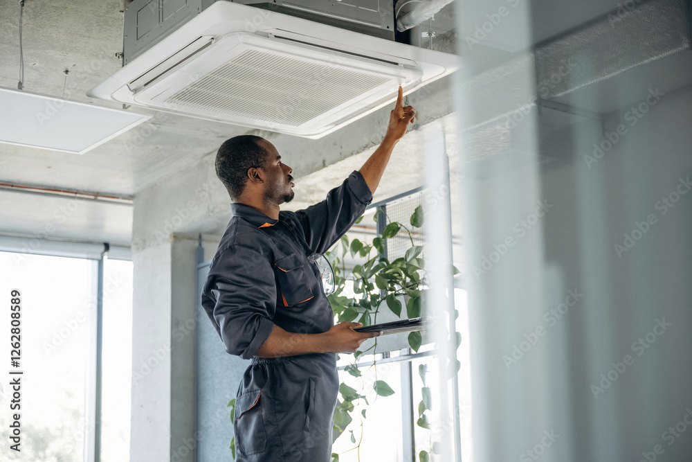 High up, fixing the ventilation. Repairman is indoors in the modern office High up, fixing the ventilation. Repairman is indoors in the modern office