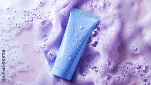 A tube placed on top of purple foam, surrounded by bubbles and suds. The background is a soft lavender color with small textures that suggest water or some kind of cleaning product