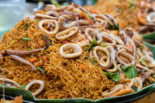 Close-up view of fried instant noodles with succulent shrimp, squid, tender octopus, and vegetable.