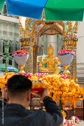 A man can be seen offering prayers at the Erawan Shrine in Bangkok, Thailand.