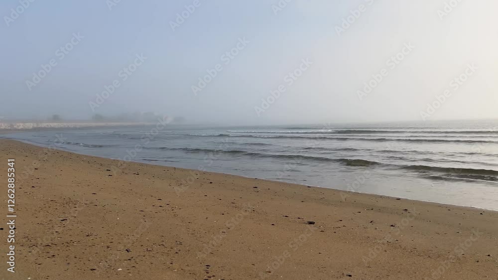 Beautiful seascape. Small waves on the sand beach. Calm sea in the morning. Horizon in the fog. Beautiful seascape. Small waves on the sand beach. Calm sea in the morning. Horizon in the fog.