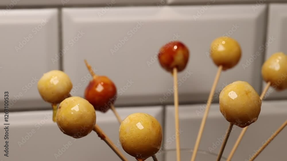 Coconut balls on wooden skewers during the preparation process of Brazilian dessert bala baiana. Coconut balls on wooden skewers during the preparation process of Brazilian dessert bala baiana.