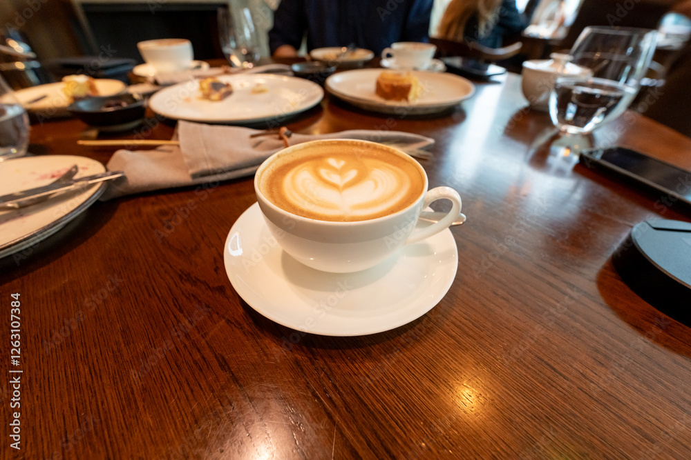 Obraz premium A hot latte with beautiful foam art sits alongside an English breakfast on a rustic wooden table, ideal for showcasing the comfort and charm of cafes and morning dining.