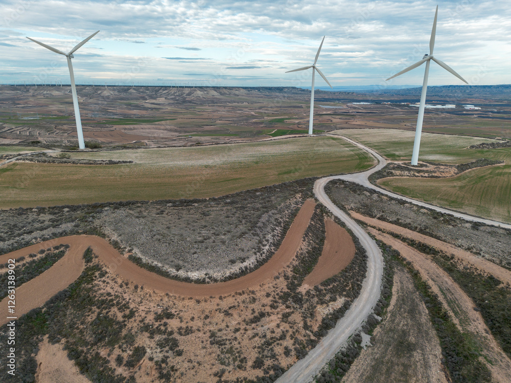 Aerial shot of a modern wind farm in Zaragoza, Spain, with sleek turbines rising above the rural landscape. The scene highlights renewable energy and sustainable infrastructure. Aerial shot of a modern wind farm in Zaragoza, Spain, with sleek turbines rising above the rural landscape. The scene highlights renewable energy and sustainable infrastructure.