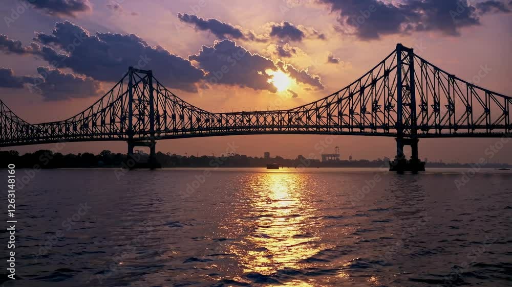 Sunset video of a bridge silhouetted against a vibrant sky, captured from a low angle over water, highlighting the bridge's intricate design. Sunset video of a bridge silhouetted against a vibrant sky, captured from a low angle over water, highlighting the bridge's intricate design.