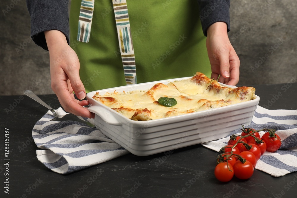 Woman with delicious spinach lasagne at grey table, closeup Woman with delicious spinach lasagne at grey table, closeup
