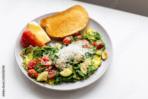 Healthy breakfast, an omelet with tomatoes, zucchini, and arugula, along with an apple and bread photo