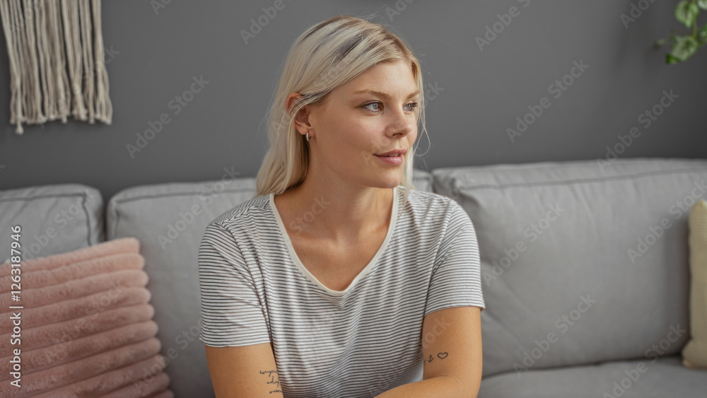 Young woman sitting in a living room with a thoughtful expression and blonde hair, wearing a striped shirt, surrounded by cozy decor on a modern couch Young woman sitting in a living room with a thoughtful expression and blonde hair, wearing a striped shirt, surrounded by cozy decor on a modern couch