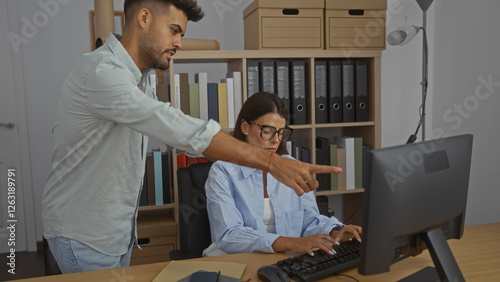 Obraz na płótnie Man assisting woman in a modern office environment with bookshelves and files, i