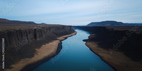 A river flows through a canyon with a blue sky in the background. The water is calm and the sky is clear
