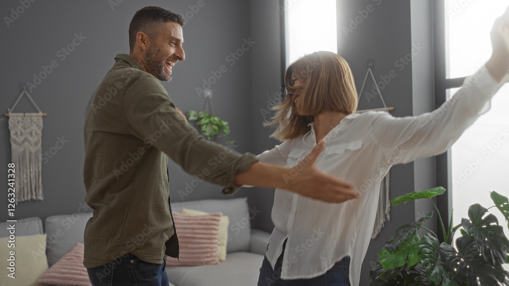 Fototapeta premium Happy couple dancing together in a cozy living room filled with plants, highlighting their joyous relationship and beautiful bond at home.