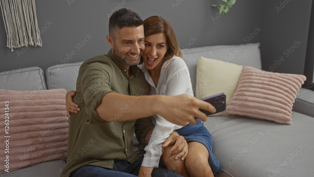 Happy couple taking selfie together indoors at home, capturing a joyful moment in their living room with cozy decor and warm ambiance, showcasing love and happiness Happy couple taking selfie together indoors at home, capturing a joyful moment in their living room with cozy decor and warm ambiance, showcasing love and happiness