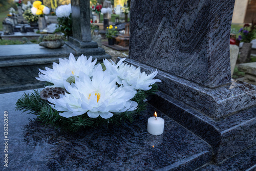 Fototapeta Naklejka Na Ścianę i Meble -  Grave with white flowers and a white candle