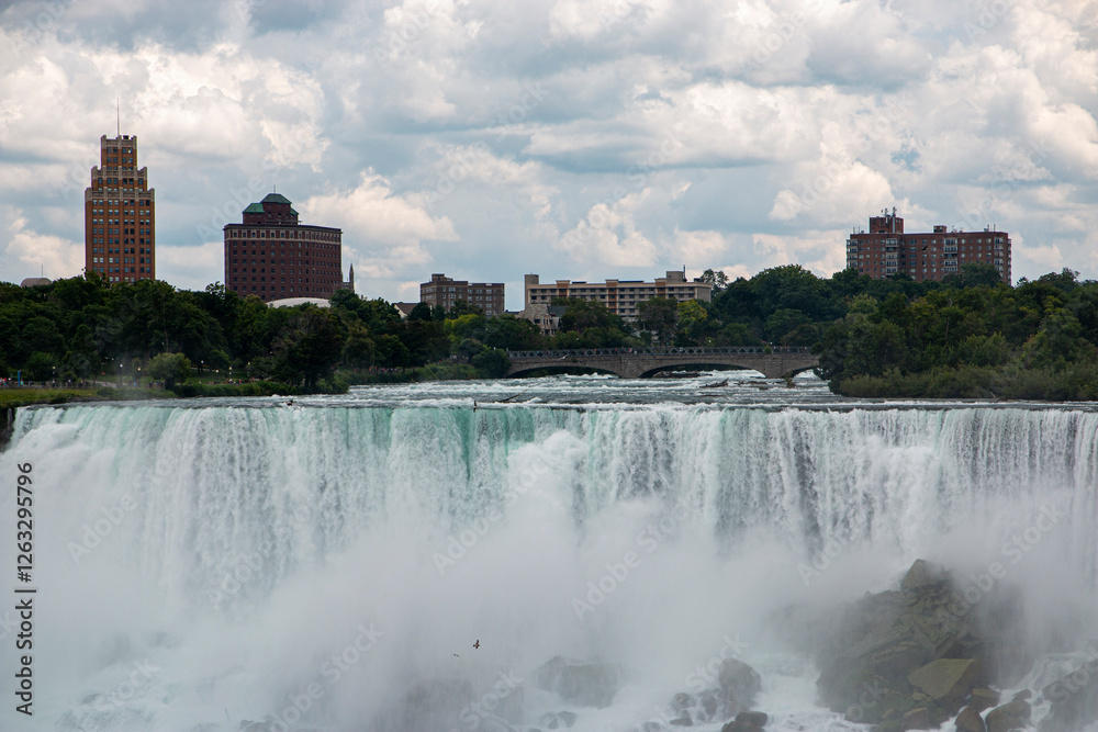 Majestic View of Niagara Falls With City Skyline Under a Cloudy Sky Majestic View of Niagara Falls With City Skyline Under a Cloudy Sky