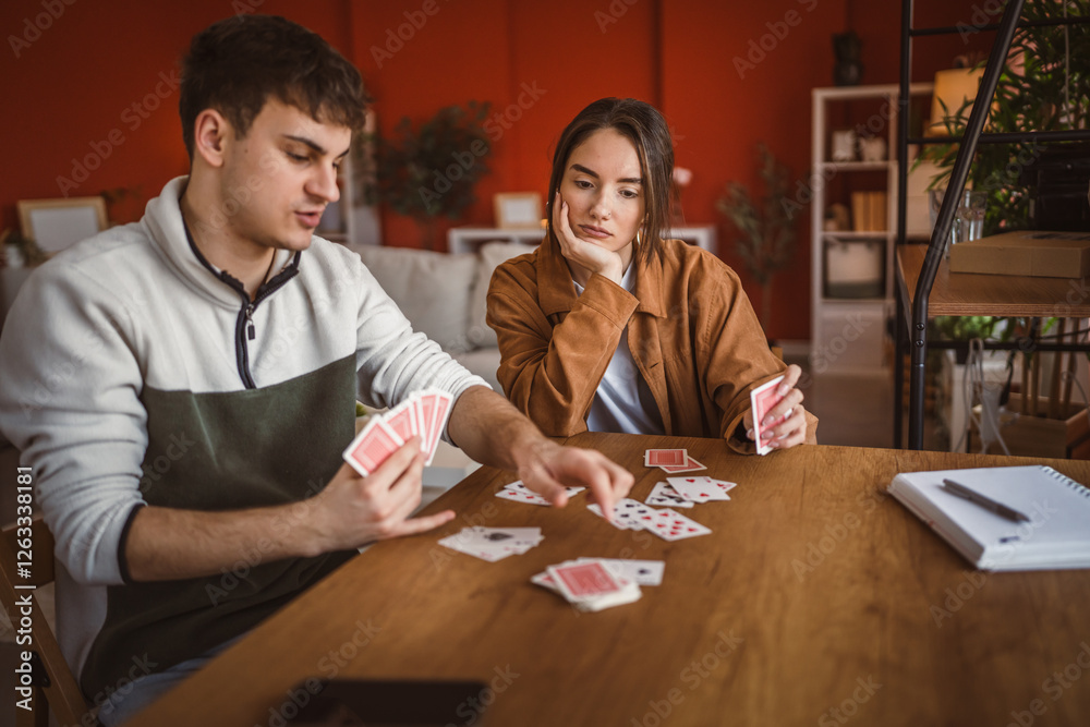 Fototapeta premium young couple boyfriend and girlfriend play cards at home