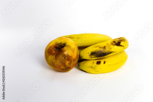 Rotten apple and overripe bananas on white background photo