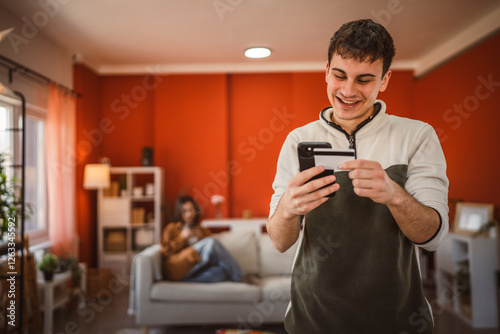 young man buy online with mobile phone and credit card at home photo