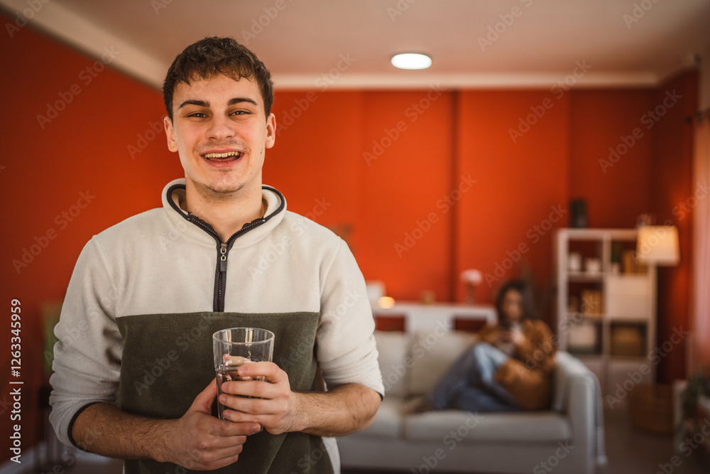 Portrait of handsome young man stand and hold glass of water at home Portrait of handsome young man stand and hold glass of water at home