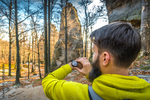 Over the shoulder view of man checking altitude on digital wristwatch during mountain hike. Outdoor adventure and navigation concept