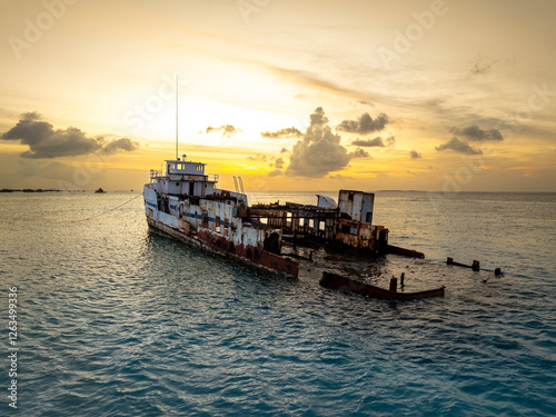 Obraz na płótnie Sunset landscape with a half sunken ship at Maldives, Indian ocean. Big rusty ship is on this photo in a lagoon. w salonie